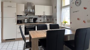 A modern kitchen with white cabinets, a wooden dining table, and black chairs.