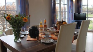 Un'area pranzo con un tavolo apparecchiato per la colazione, con piatti, bicchieri e un vaso di fiori.