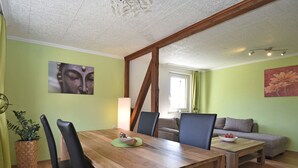 A dining area with a wooden table and chairs, a sofa, and a painting on the wall.