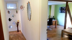 A hallway with a wooden floor, a mirror, and a vase with flowers.