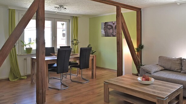 A living room with a wooden coffee table, a sofa, and a dining area with chairs and a table.