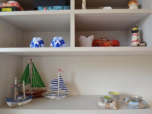 A shelf with various items including a model ship, a toy car, and a lighthouse. - Holiday Home in Carrara by the Sea (Carrara)