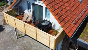 A modern house with a red-tiled roof, a wooden deck, and a small outdoor seating area. - Ferienhaus in Obernburg am Edersee (Voehl)
