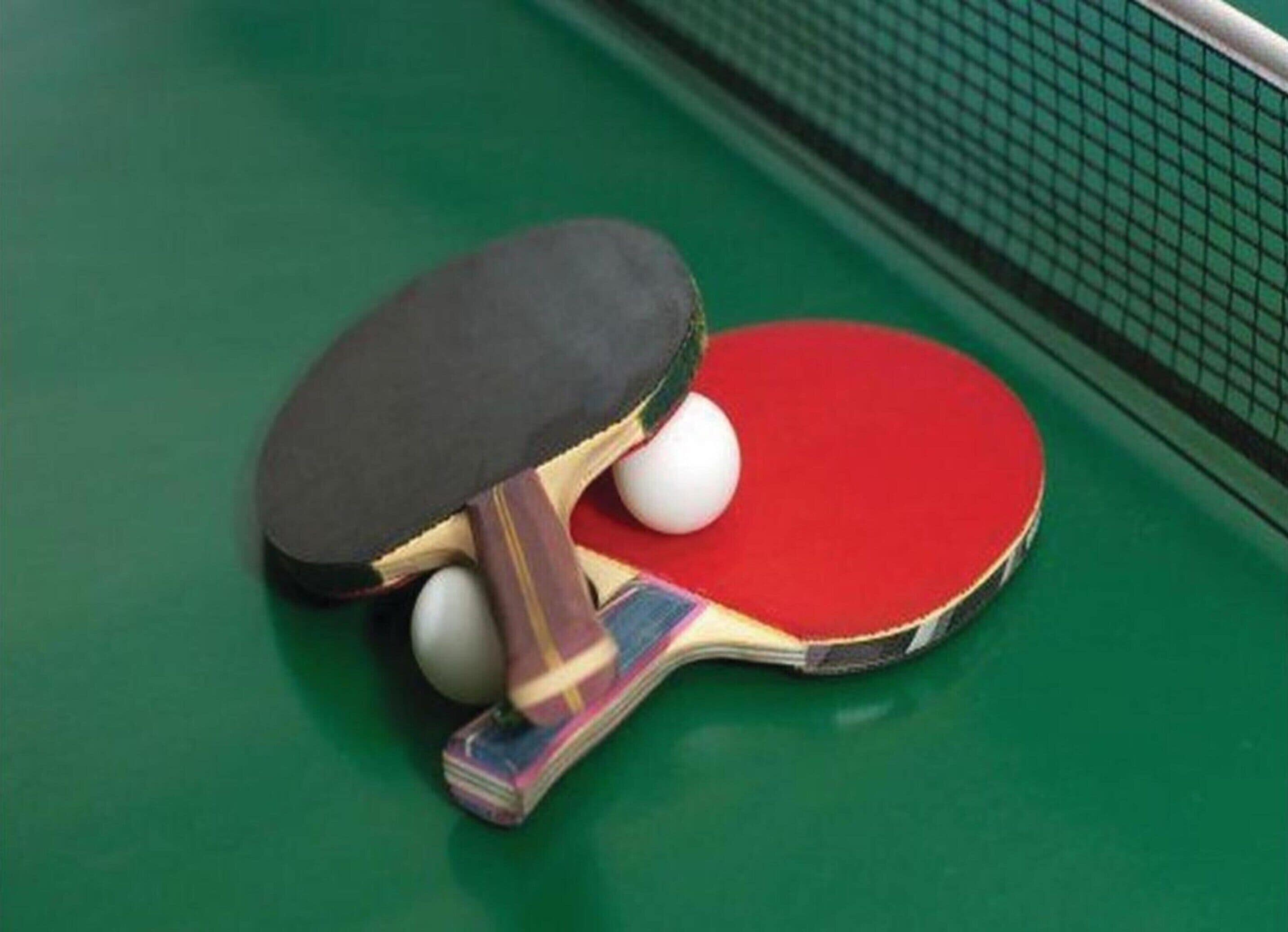 A table tennis table with a net and two paddles with balls.