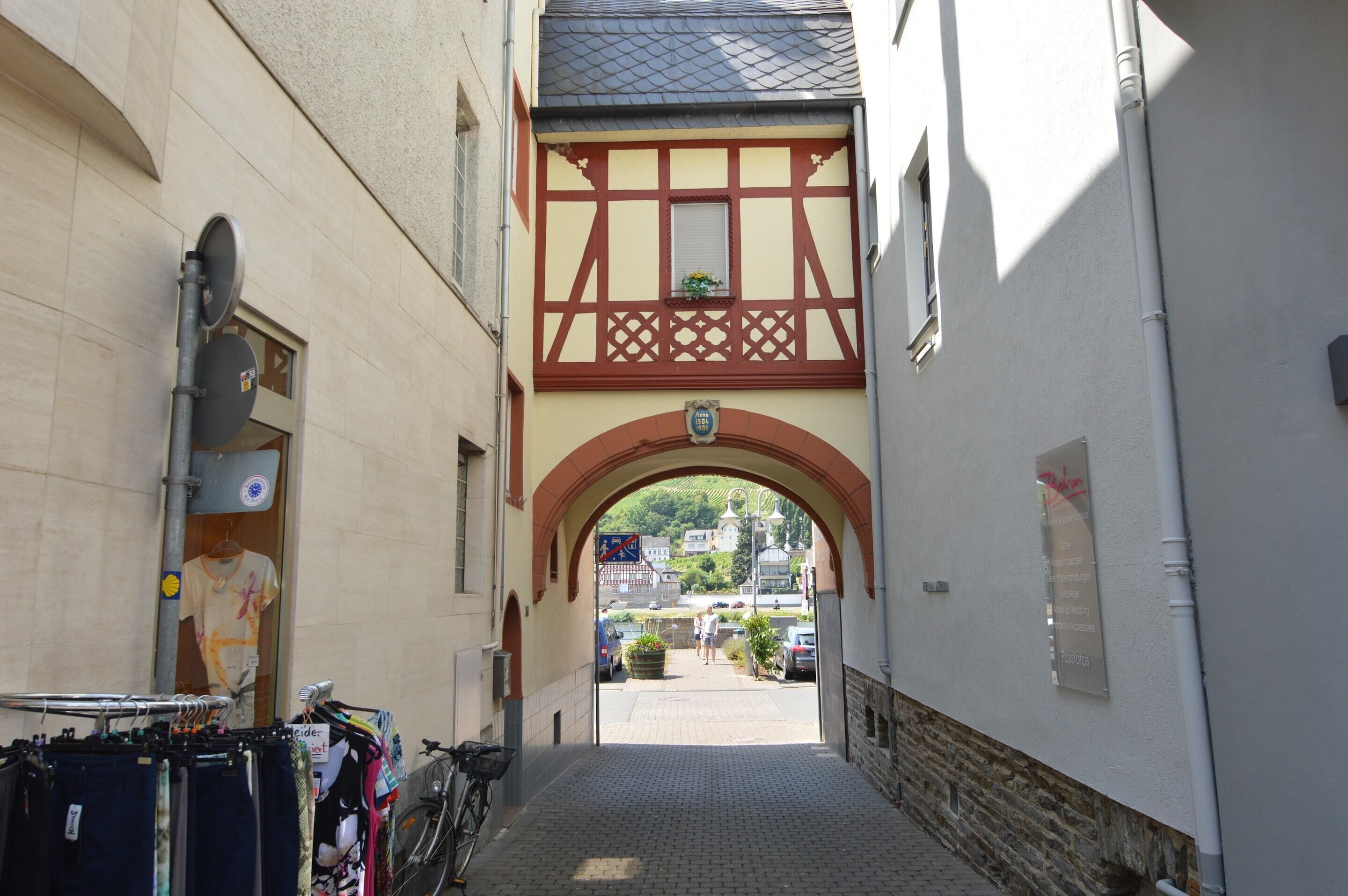 A narrow alleyway with a half-timbered building, a bicycle, and a clothing rack.