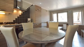 Una cocina moderna con una mesa redonda de vidrio, sillas blancas y una estufa empotrada.