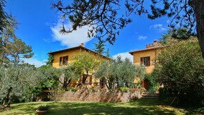 A two-story yellow building with a brick wall and a wooden fence in a garden. - Farmhouse in Todi With Pool & Theater Nearby (Todi)