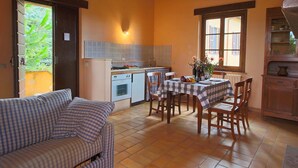 A cozy kitchen with a dining area, featuring a checkered tablecloth, wooden chairs, and a striped sofa. - Farmhouse in Todi With Pool & Theater Nearby (Todi)