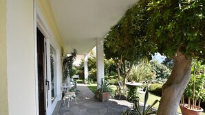 Un patio couvert avec un sol en pierre, des plantes en pot et du mobilier d’extérieur.