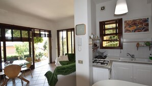 Un salon avec un canapé, une table à manger avec des chaises et un coin cuisine équipé d’une cuisinière et d’un évier.