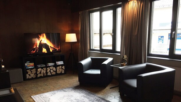 A living room with a fireplace, a television, two armchairs, a rug, and a window with curtains. - Holiday Home Fabryshof in Bollendorf (Bollendorf)