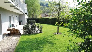 A well-maintained courtyard with a neatly trimmed lawn, a small tree, and a stack of firewood. - Holiday Home Fabryshof in Bollendorf (Bollendorf)
