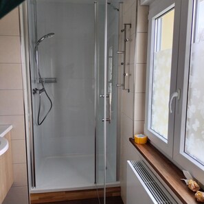 A modern bathroom with a glass shower enclosure, a toilet, and a window with frosted glass. - Stay With Garden in the Hunsruck (Stipshausen)