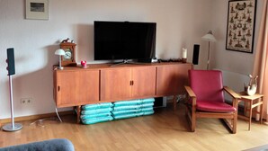 A living room with a television, a red chair, a sofa, and a wooden cabinet. - Stay With Garden in the Hunsruck (Stipshausen)