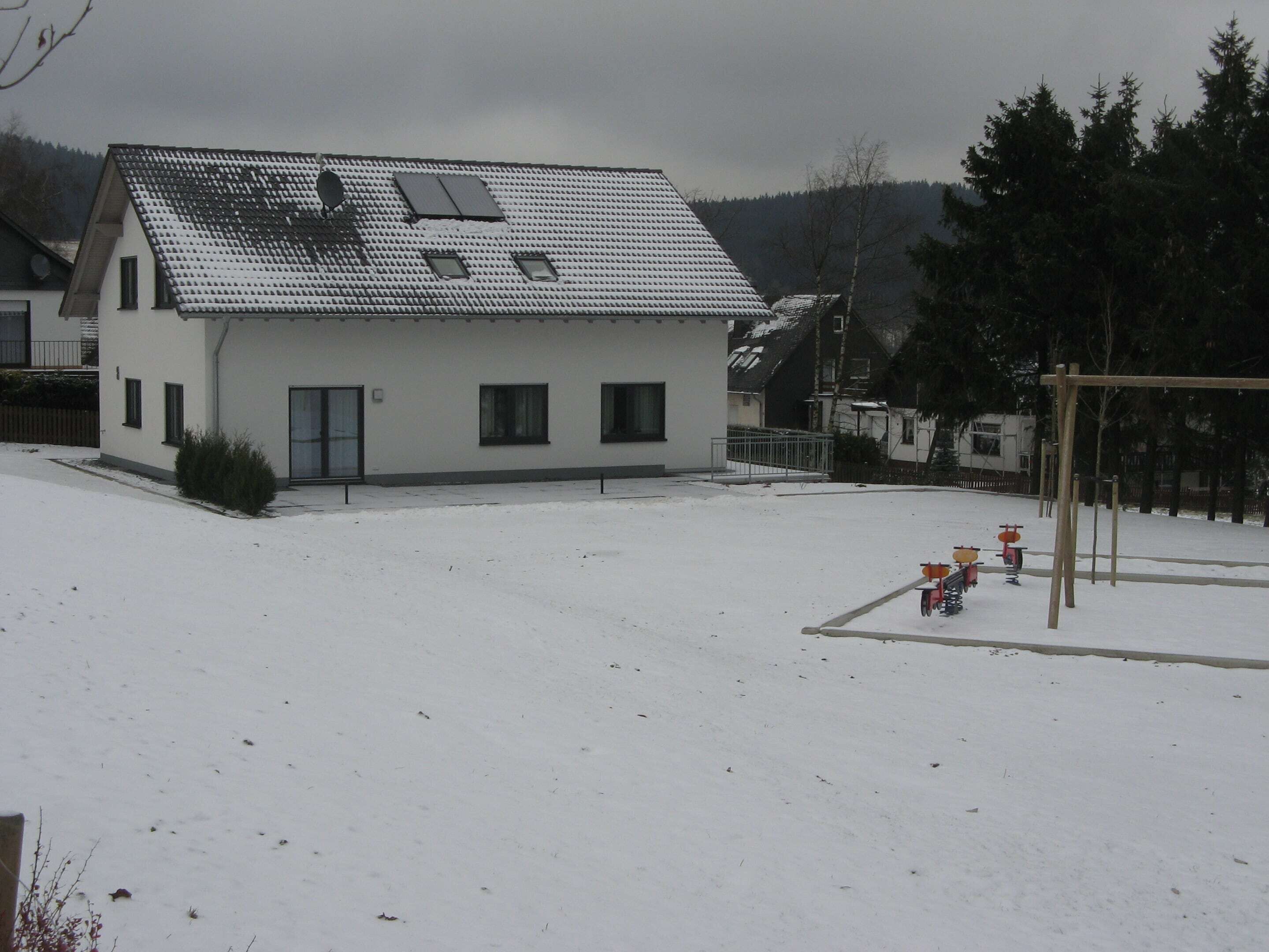A two-story house with a sloped roof, a satellite dish, and a fenced yard.