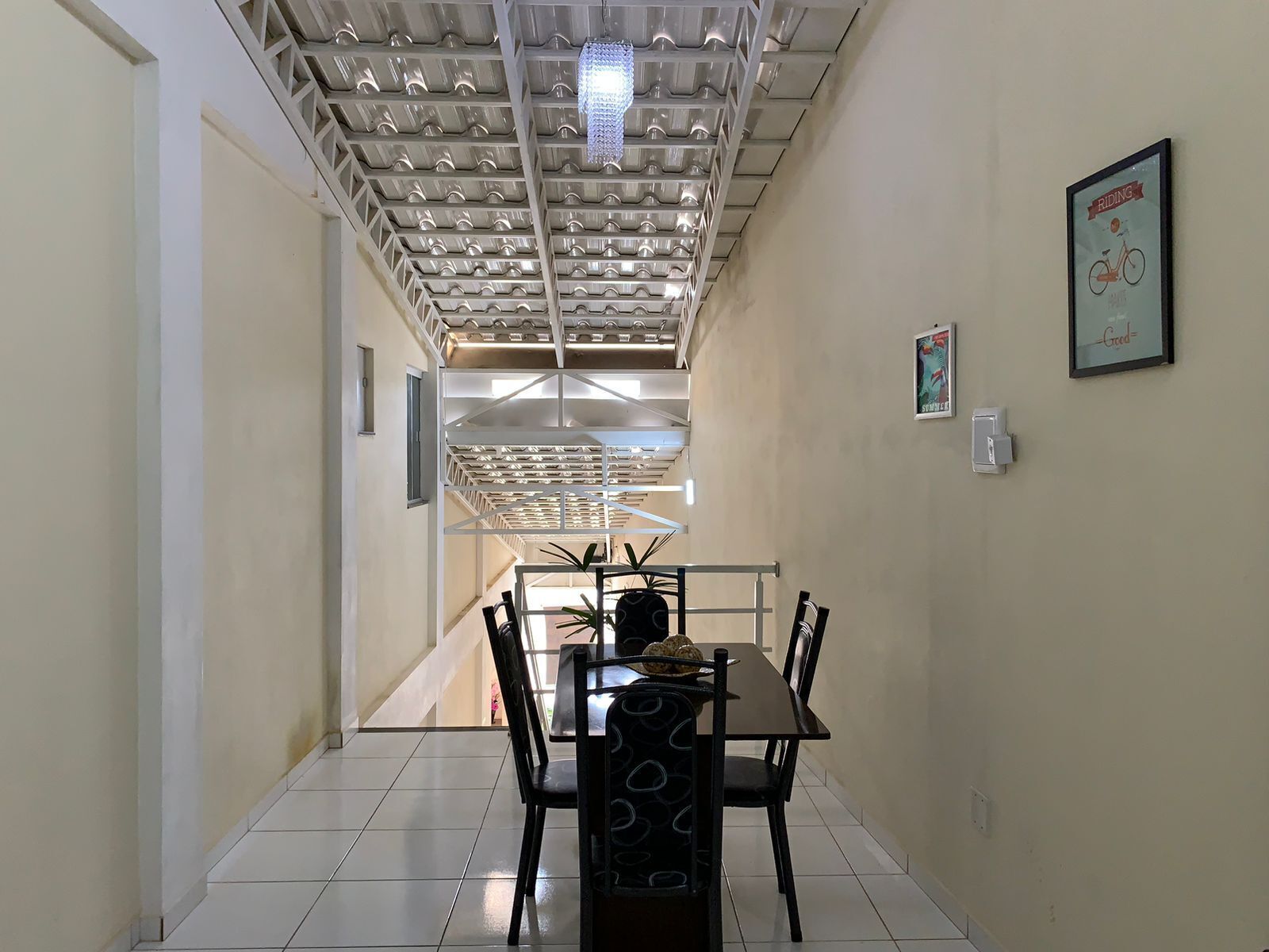 A dining area with a table and chairs, a ceiling with a grid-like structure, and a poster on the wall.