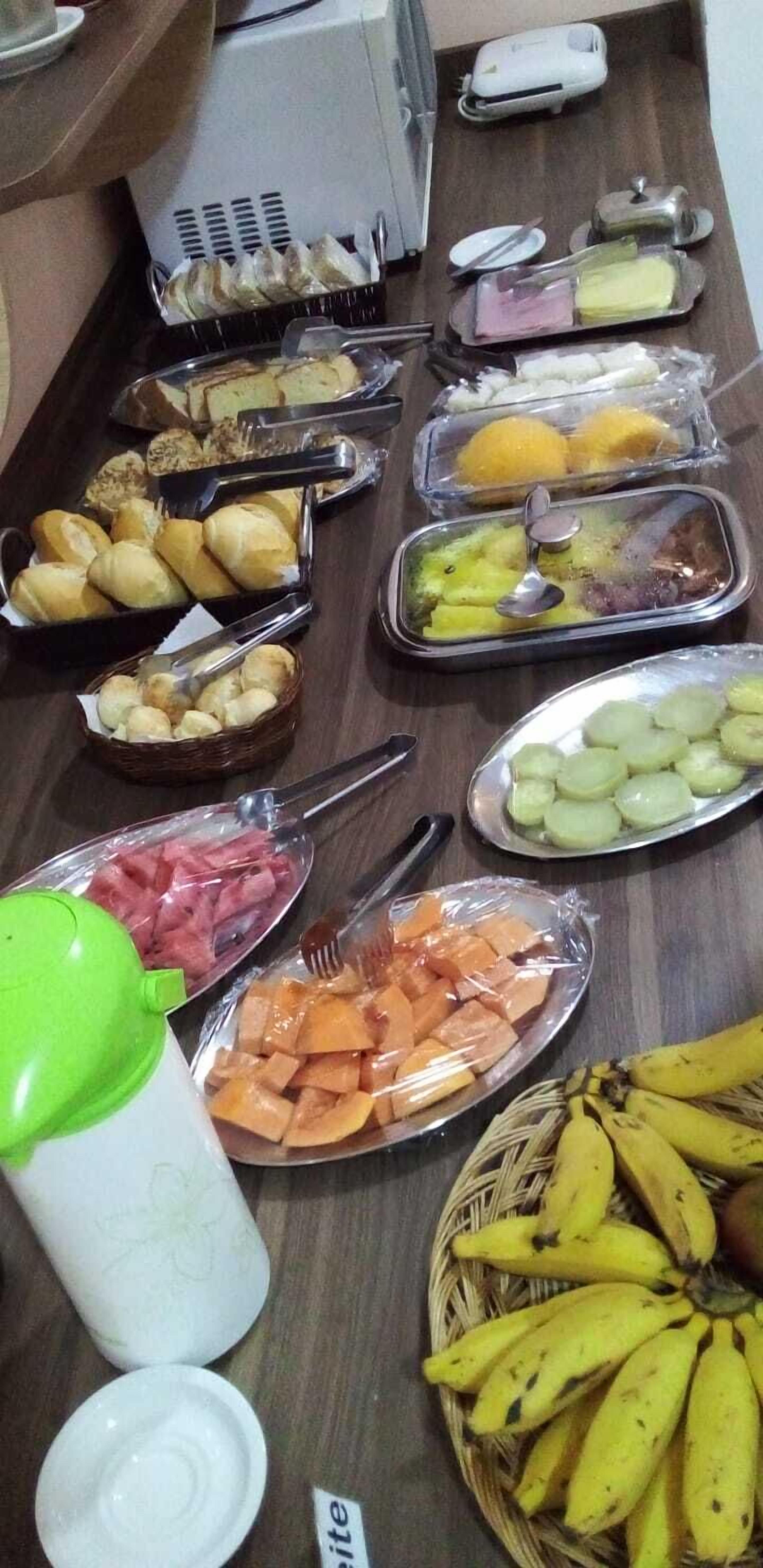 Una mesa de buffet con diferentes alimentos, entre ellos pan, frutas y verduras.