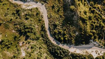 Vista aérea de una carretera sinuosa que atraviesa un área boscosa con abundante vegetación a ambos lados.