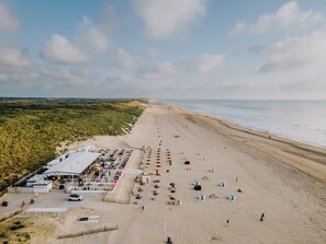 Ein Hotel direkt am Strand mit Essbereich, Strandsonnenschirmen und einem Sandstrand.