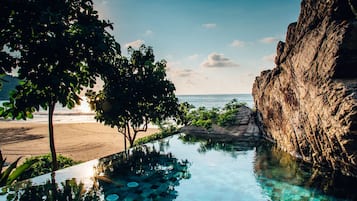 Relax by the serene pool overlooking the ocean and lush greenery.
