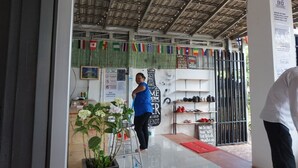 Une devanture de magasin avec un toit en métal, une enseigne affichant divers messages et une vitrine remplie de chaussures.