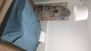 Ett rum med en säng, ett skrivbord, en spegel och en hylla med diverse föremål.