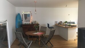 En matplats med ett träbord, stolar och en surfbräda som dekoration.