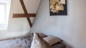 Une chambre à coucher avec un lit, une poutre en bois et une œuvre d’art encadrée au mur.