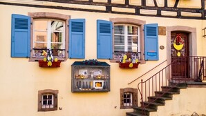 Un bâtiment traditionnel à colombages, doté de nombreuses fenêtres, d’une entrée bien visible et situé sur une rue pavée.