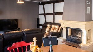 Un salon avec une cheminée, un canapé en cuir et une table sur laquelle se trouve une bouteille.