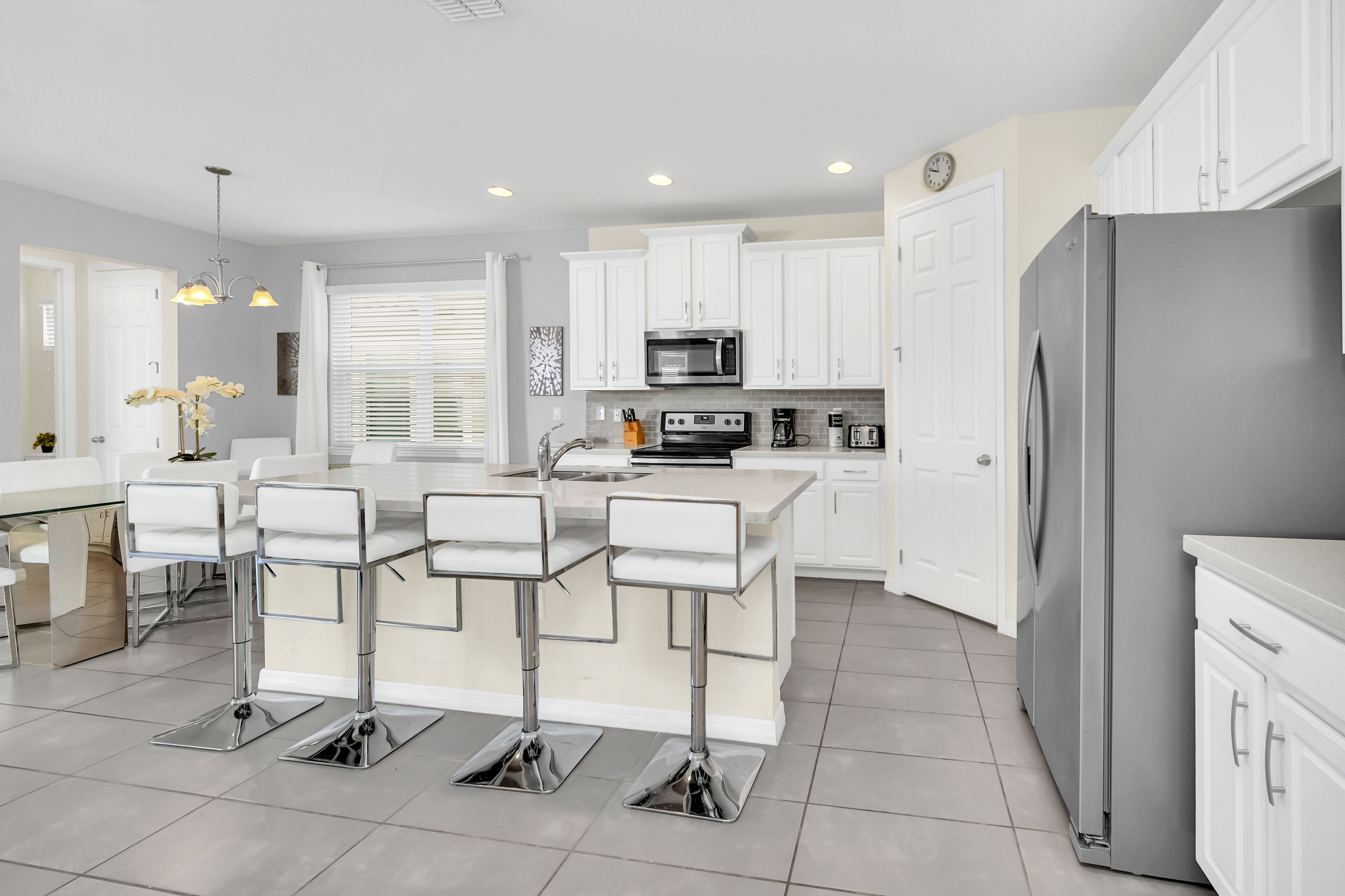 A modern kitchen with white cabinets, stainless steel appliances, and a central island with bar stools.