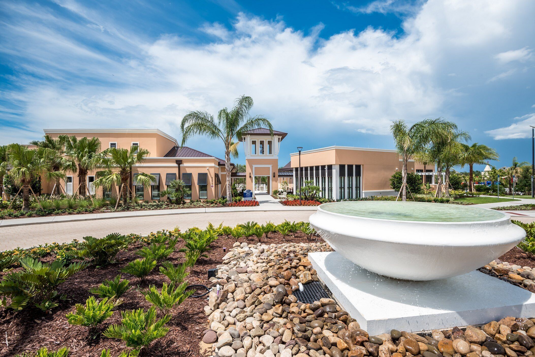 A resort with a central tower, palm trees, and a large fountain.