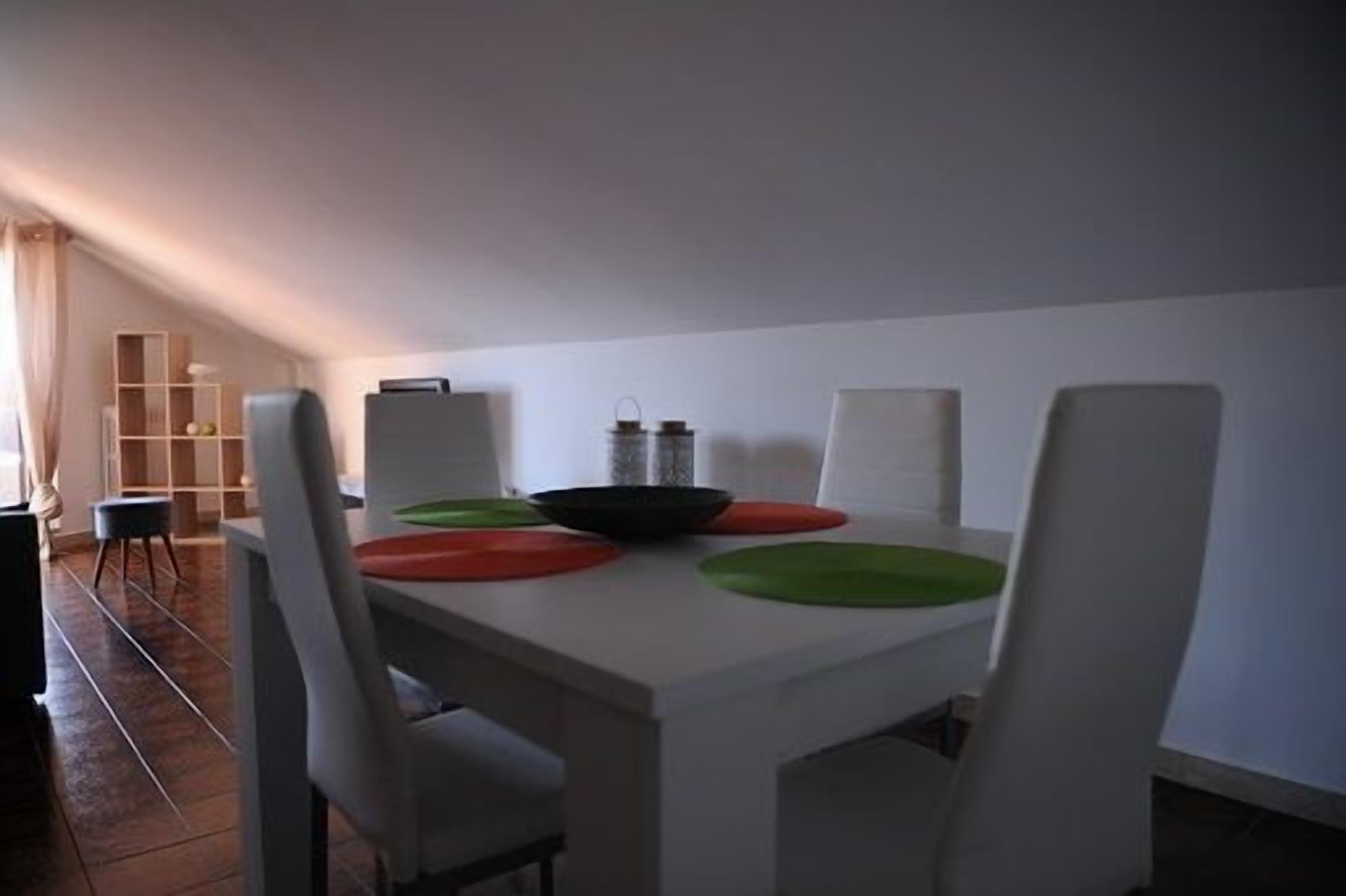 A dining area with a white table, four chairs, and colorful placemats.