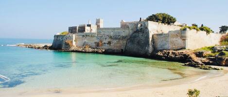 A coastal fortification with a clear view of the sea and a sandy beach.