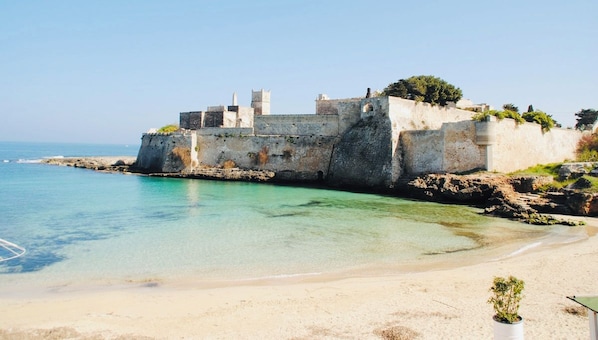 A coastal fortification with a clear view of the sea and a sandy beach.