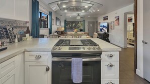 Una cocina moderna con una isla central, horno empotrado y un amplio ventanal.