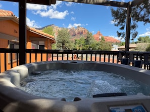 Un jacuzzi con vistas a formaciones rocosas rojas y un cielo despejado.