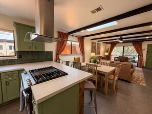 A modern kitchen with a central island, dining area with chairs, and a living space with a couch and a table. - Uptown House+Walkable+Full Kitchen+SelfCkin+PetsOK+Hot Tub, The Uptown House~Red Rock Getaway (Sedona)