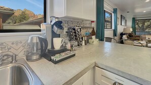Una cocina moderna con cafetera, infusor de té y diversos utensilios de cocina.