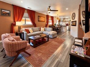 A modern living room with a sofa, chairs, a coffee table, and a dining area with a kitchen in the background. - Bicycle House Just Steps to Uptown, Trail Close,, The Bicycle House~ Red Rock Getaway (Sedona)