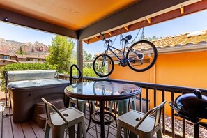 A patio with a hot tub, a round table, chairs, a barbecue grill, and a bicycle. - The Bicycle House | Hot Tub• Bike-Friendly Retreat, The Bicycle House~ Red Rock Getaway (Sedona)