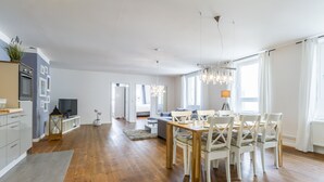 Amplia sala de estar con piso de madera, una mesa de comedor con sillas, un sofá y un televisor.