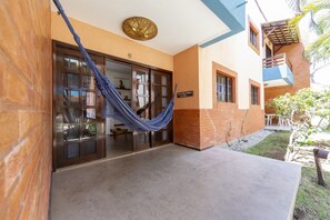 A building entrance with a blue hammock, a sign reading "Hotel de la Playa", and a small outdoor seating area with tables and chairs. - Chalés Sophie Paradise (Tibau do Sul)