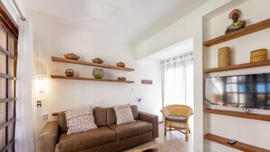 Ein Wohnzimmer mit braunem Sofa, einem Korbstuhl und Regalen mit Dekorationen.