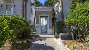 A narrow pathway leading to a gated entrance of a building with a small porch and a mailbox. - Bella Mar - Villas of Frangista, Community Pool, Walk to the Beach + Dining! (Miramar Beach)