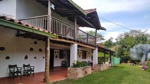 Un bâtiment à deux étages doté d’un balcon, d’un espace extérieur aménagé pour s’asseoir et d’une pelouse bien entretenue.