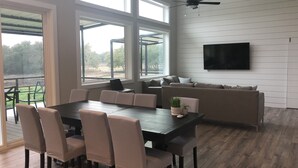 A modern living room with a dining area, large windows, a ceiling fan, and a flat-screen TV. - Modern Farmhouse - Close proximity to Southwest Austin wedding Venues (Austin)