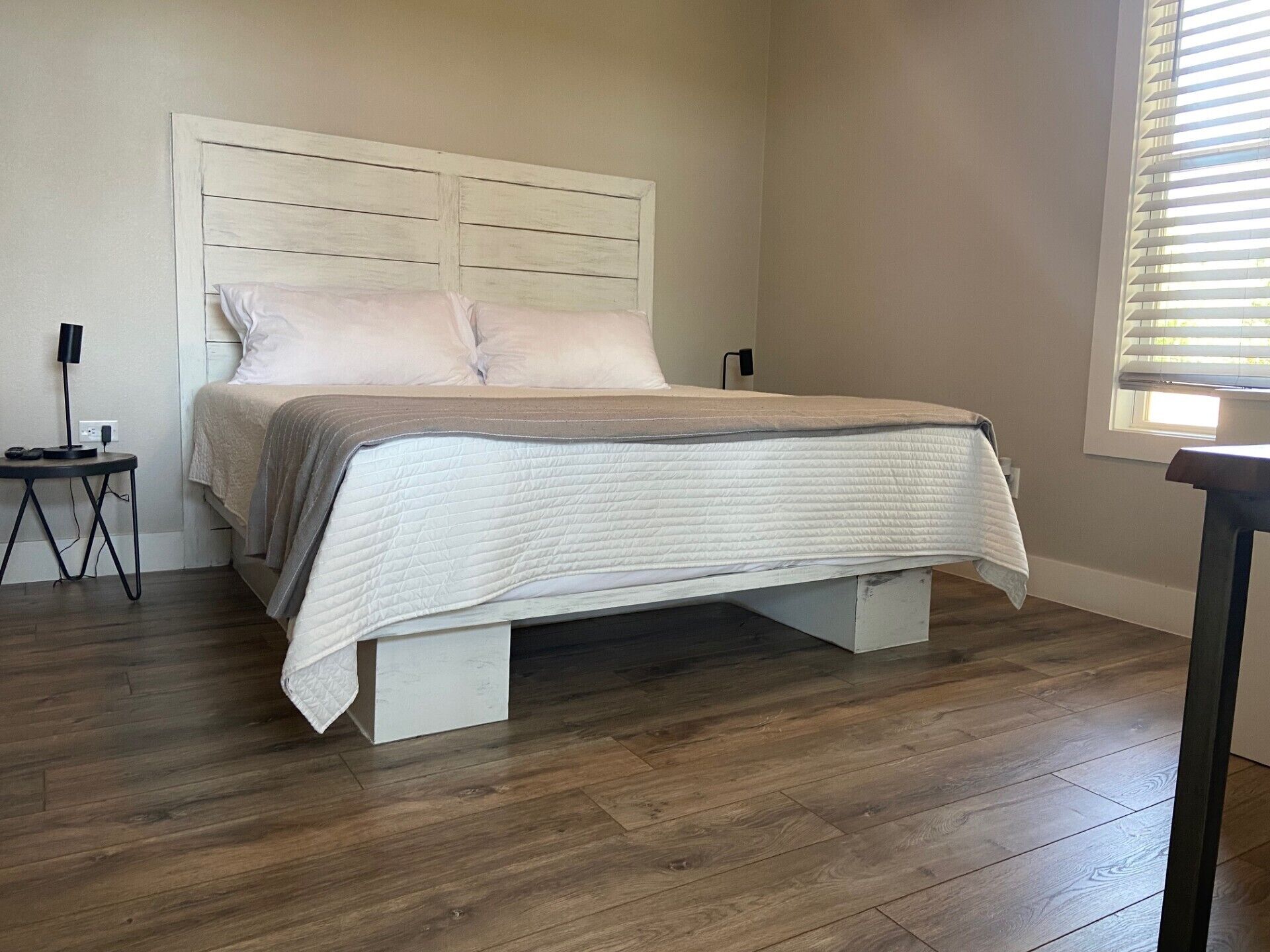 A bedroom with a bed, a bedside table, and a window.