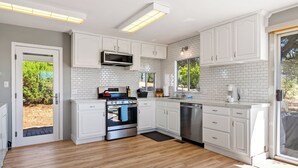 A modern kitchen with white cabinets, a stainless steel oven, and a dishwasher.