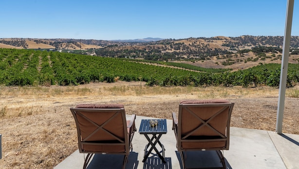 A patio with two chairs and a table overlooking a vineyard.